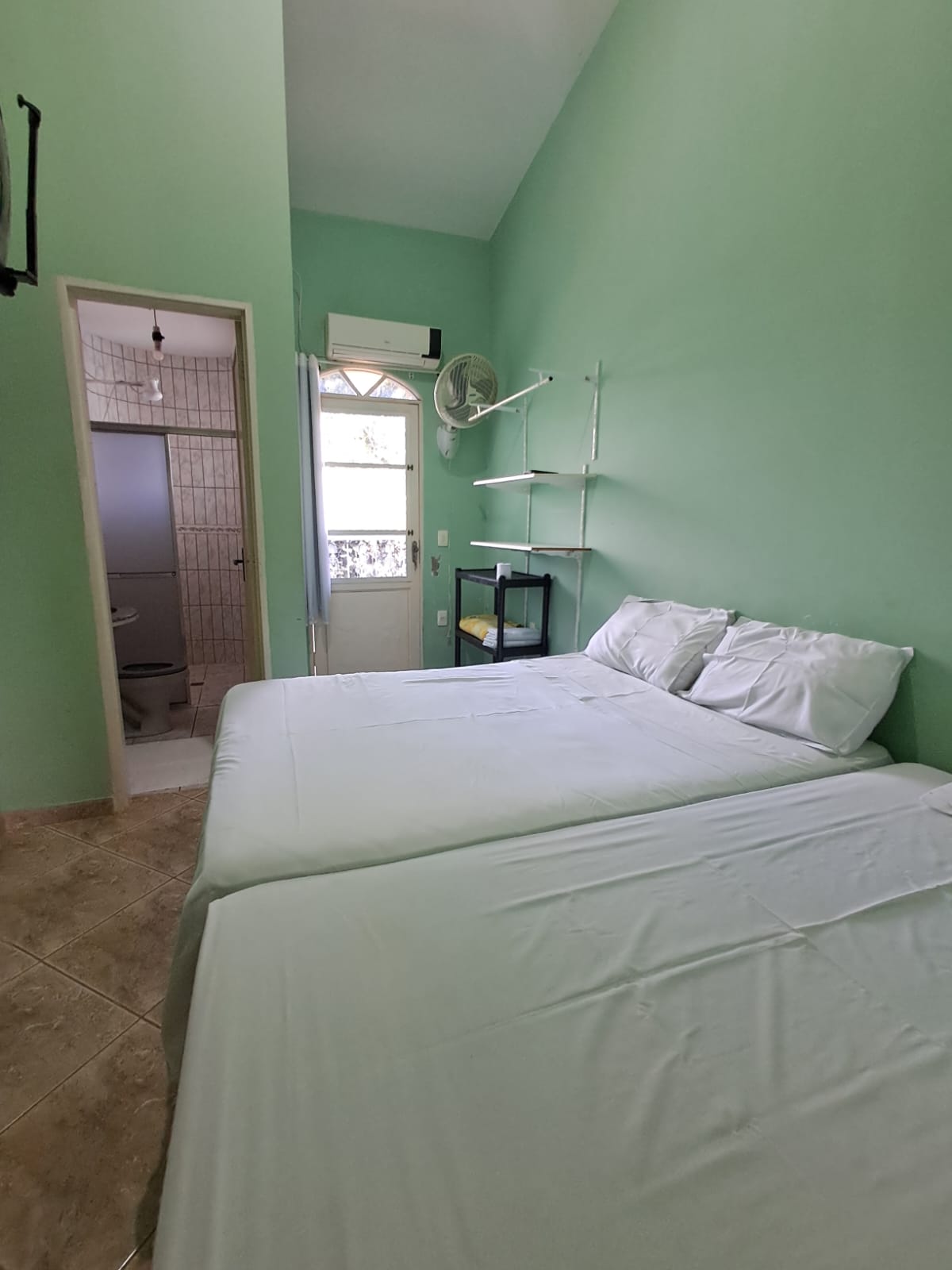 Quarto verde com duas camas de casal e ar-condicionado